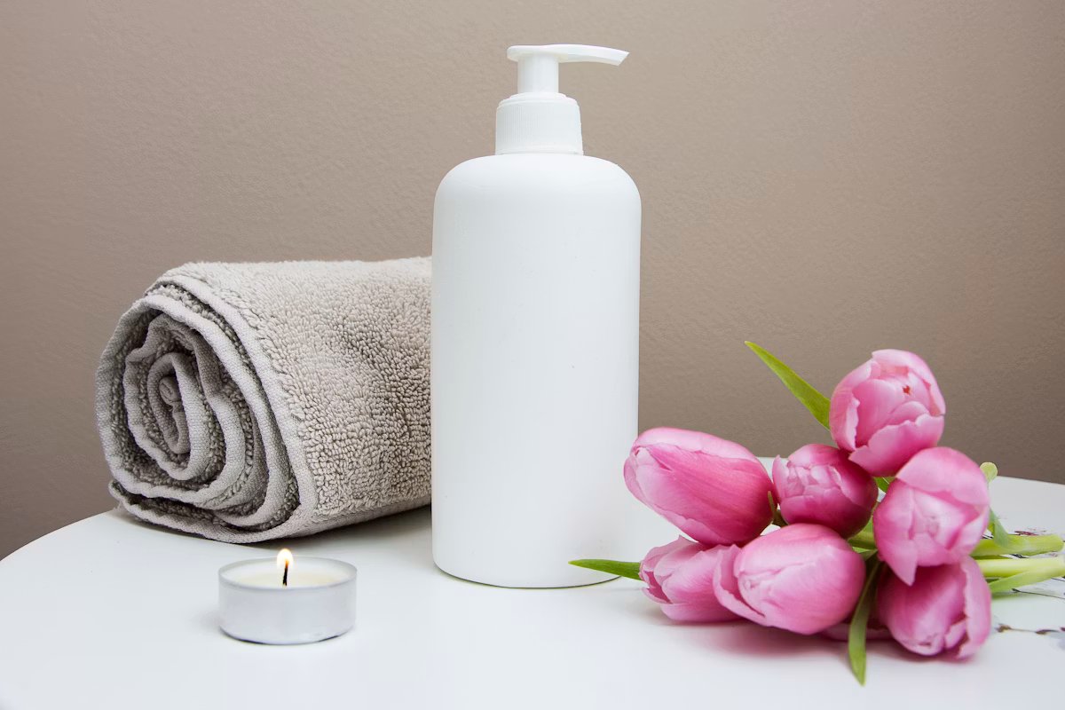 Spa still life with a lotion bottle, rolled towel, candle and tulips